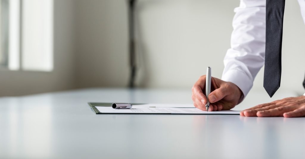 Man in white shirt signing contract or subscription form