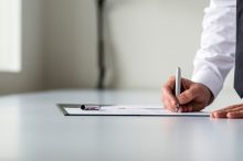 Man in white shirt signing contract or subscription form